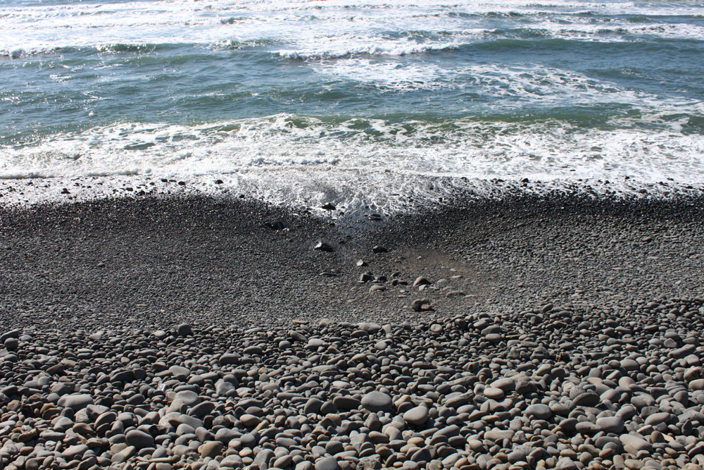Mellow surf at Falcon Cove with layers of rounded stones